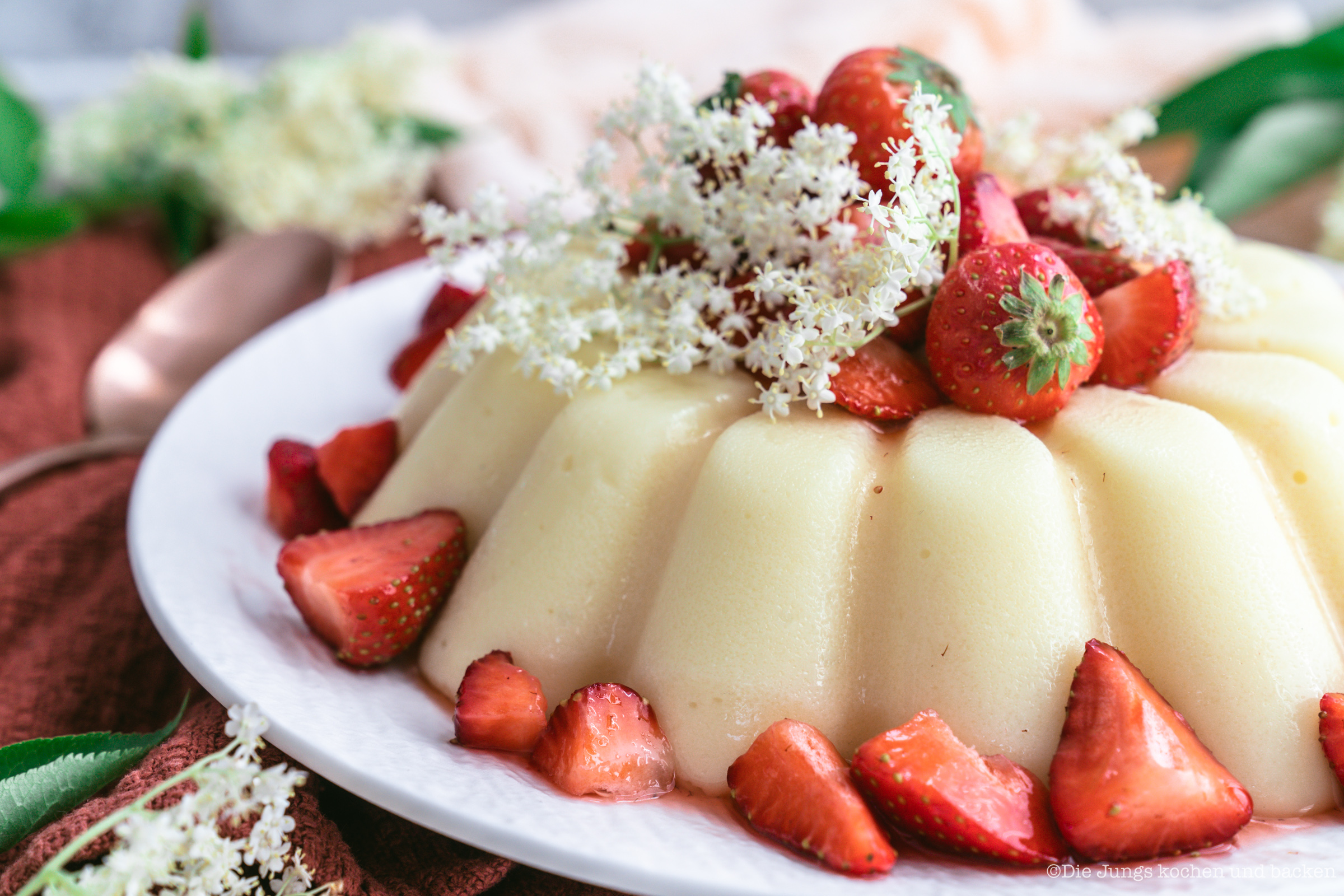 Rezept für gestürzten Holunderblütenpudding mit Erdbeeren. Ein tolles Dessert, das auch noch ein Hingucker ist! Der Pudding lässt sich easy vorbereiten und ist schnell gemacht. #holunderblütensirup #dessert #rezepte